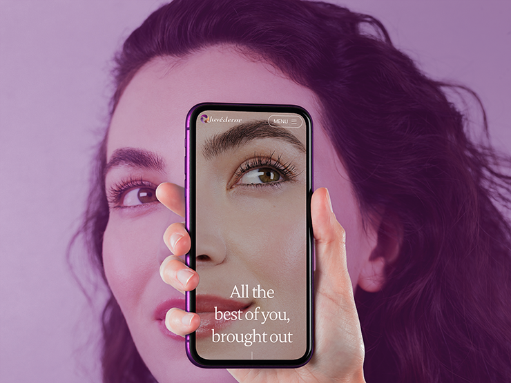 Hand holding a smartphone with Juvéderm's website